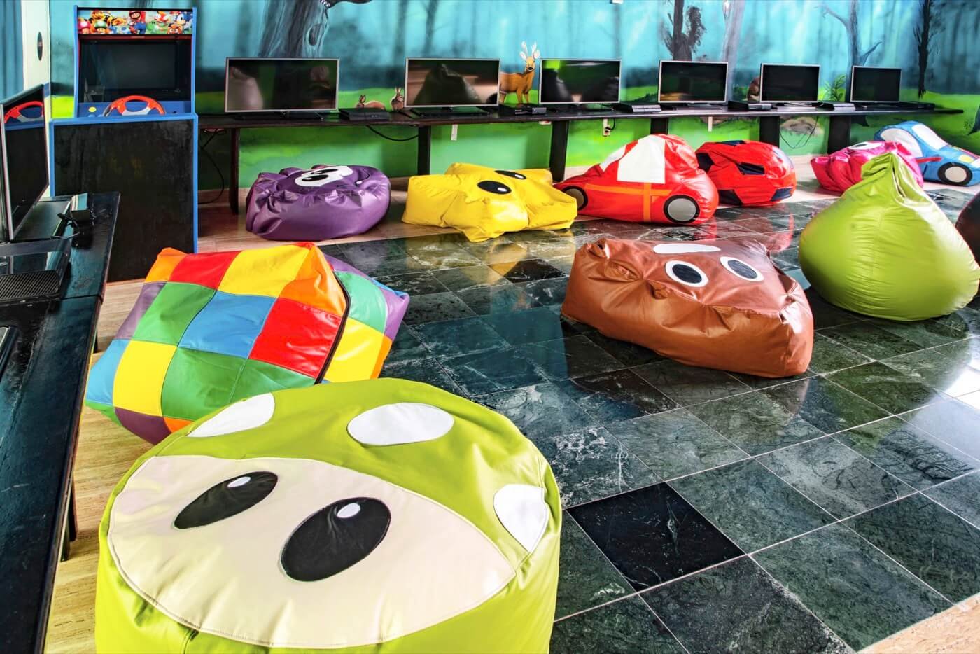 Área de juegos en KiddoZone con consolas y sillones puff en Hotel Grand Oasis Palm